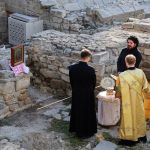 Priests conduct a religious ceremony at historical stone ruins outdoors.