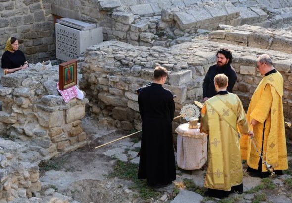 Priests conduct a religious ceremony at historical stone ruins outdoors.